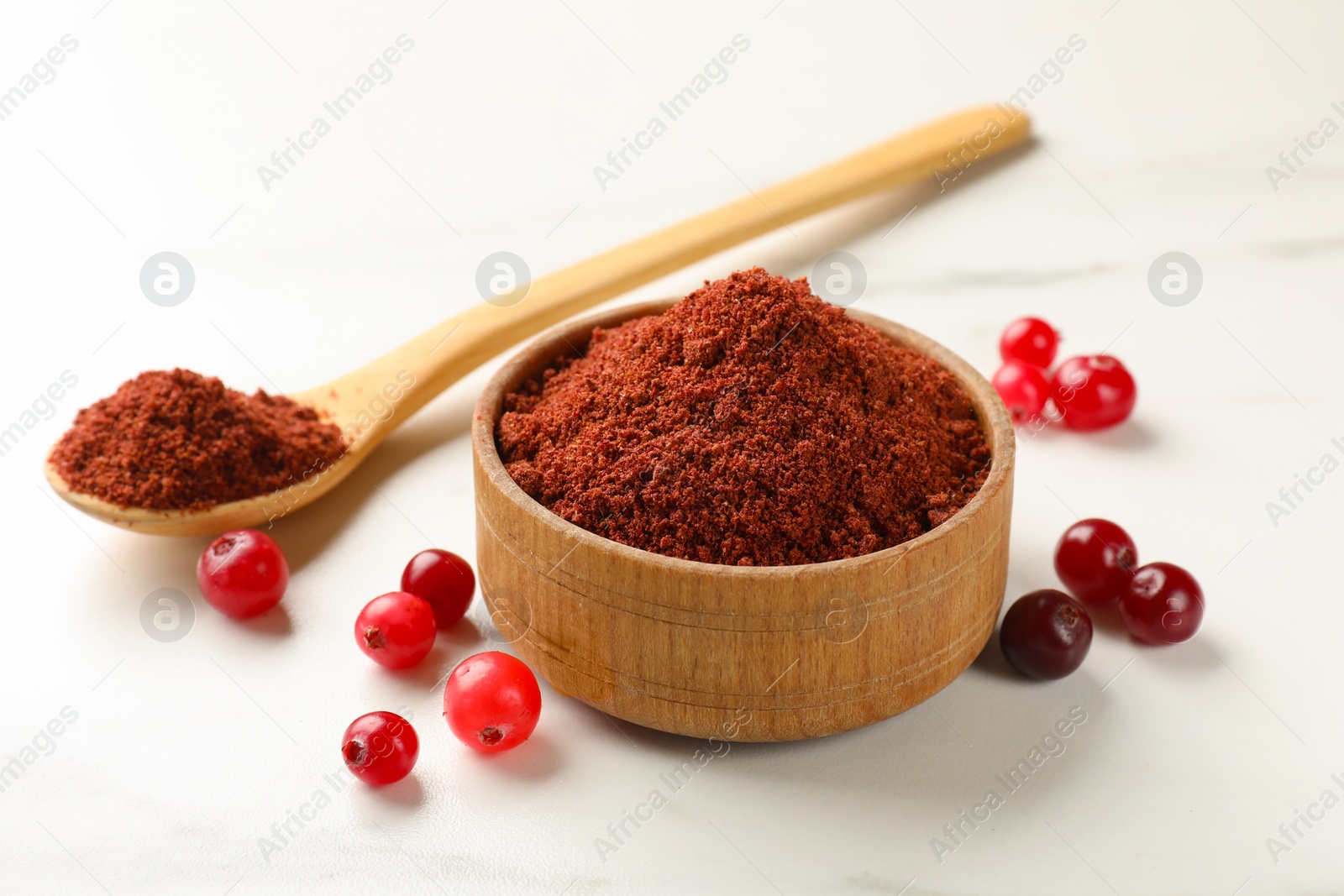 Photo of Dried cranberry powder and fresh berries on white table