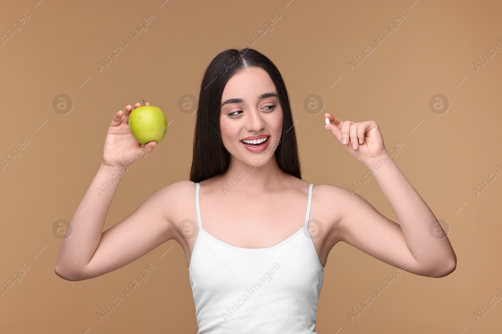 Photo of Beautiful young woman with vitamin pill and apple on beige background