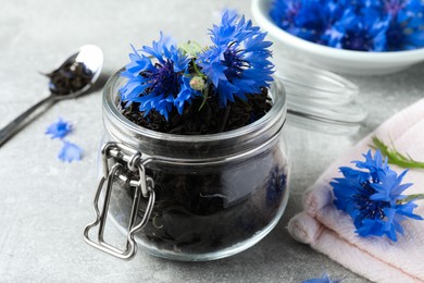 Photo of Dry tea leaves and cornflowers on light table, closeup