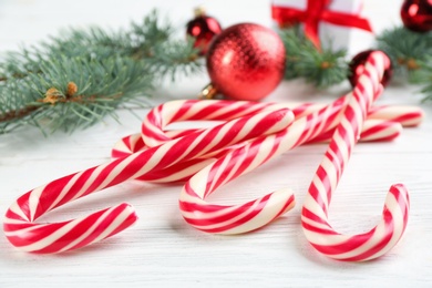 Photo of Many sweet candy canes and Christmas decor on white wooden table, closeup