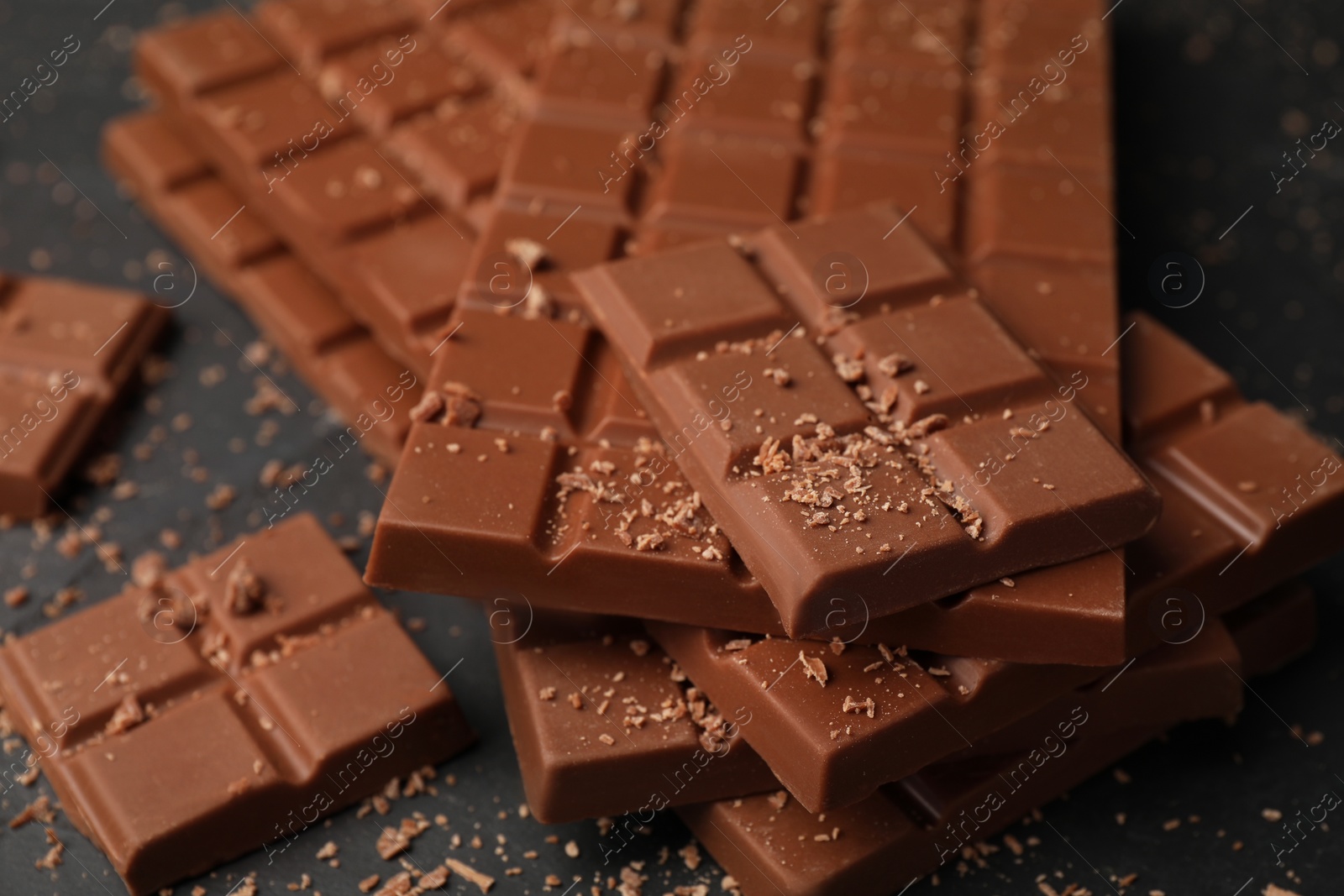 Photo of Pieces of tasty chocolate bars on grey table, closeup