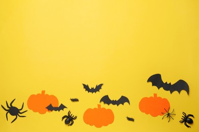 Photo of Flat lay composition with paper pumpkins, bats and spiders on pale yellow background, space for text. Halloween celebration