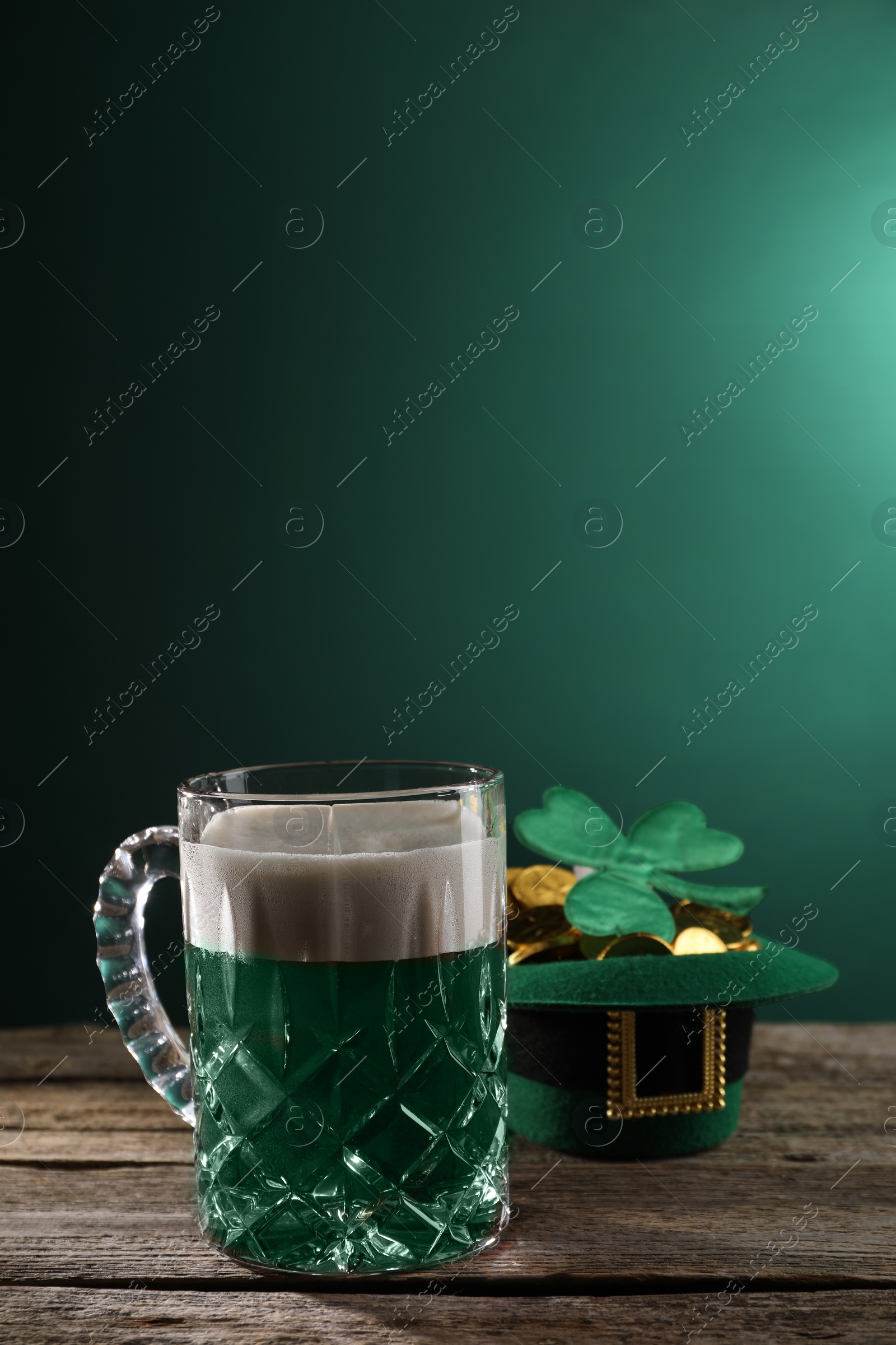 Photo of St. Patrick's day celebration. Green beer, leprechaun hat with gold and decorative clover leaf on wooden table. Space for text