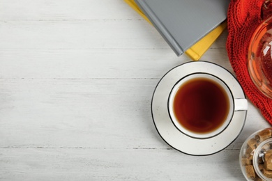 Flat lay composition with cup of hot tea on white wooden table, space for text. Winter drink