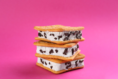 Sweet delicious ice cream cookie sandwiches on pink background