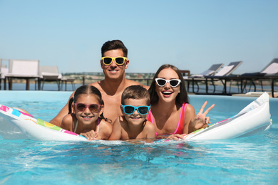 Photo of Happy family on inflatable mattress in swimming pool