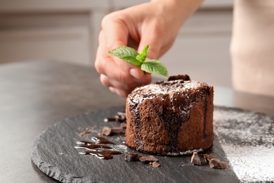 Chef decorating delicious fresh chocolate fondant with mint at table. Lava cake recipe