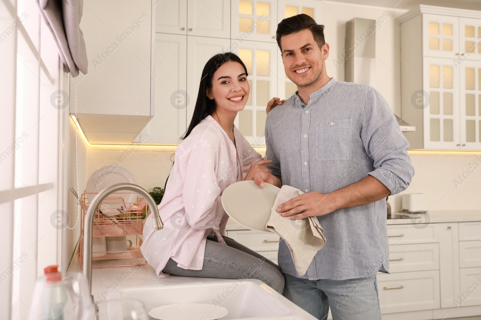 Photo of Happy couple with clean dishes in kitchen