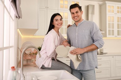 Happy couple with clean dishes in kitchen