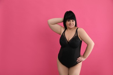 Photo of Beautiful overweight woman in black underwear on pink background, space for text. Plus-size model