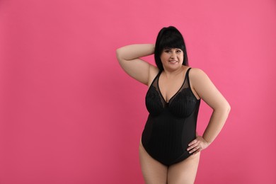 Beautiful overweight woman in black underwear on pink background, space for text. Plus-size model