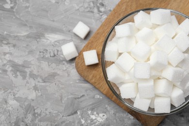 White sugar cubes in glass bowl on grey table, top view. Space for text