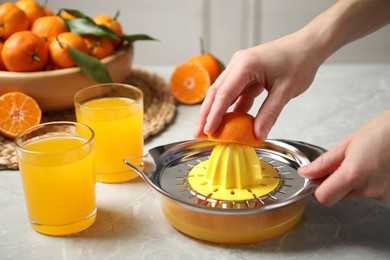 Photo of Woman making fresh tangerine juice indoors, closeup