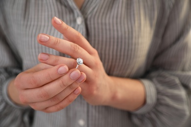 Photo of Woman taking off wedding ring, closeup. Divorce concept