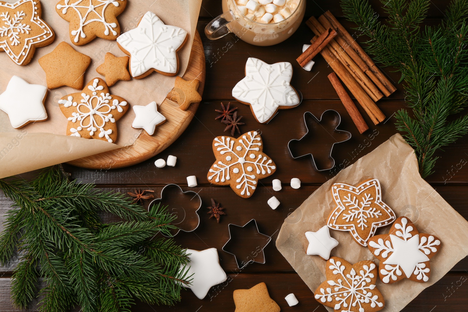 Photo of Decorated Christmas cookies and fir tree branches on wooden table, flat lay