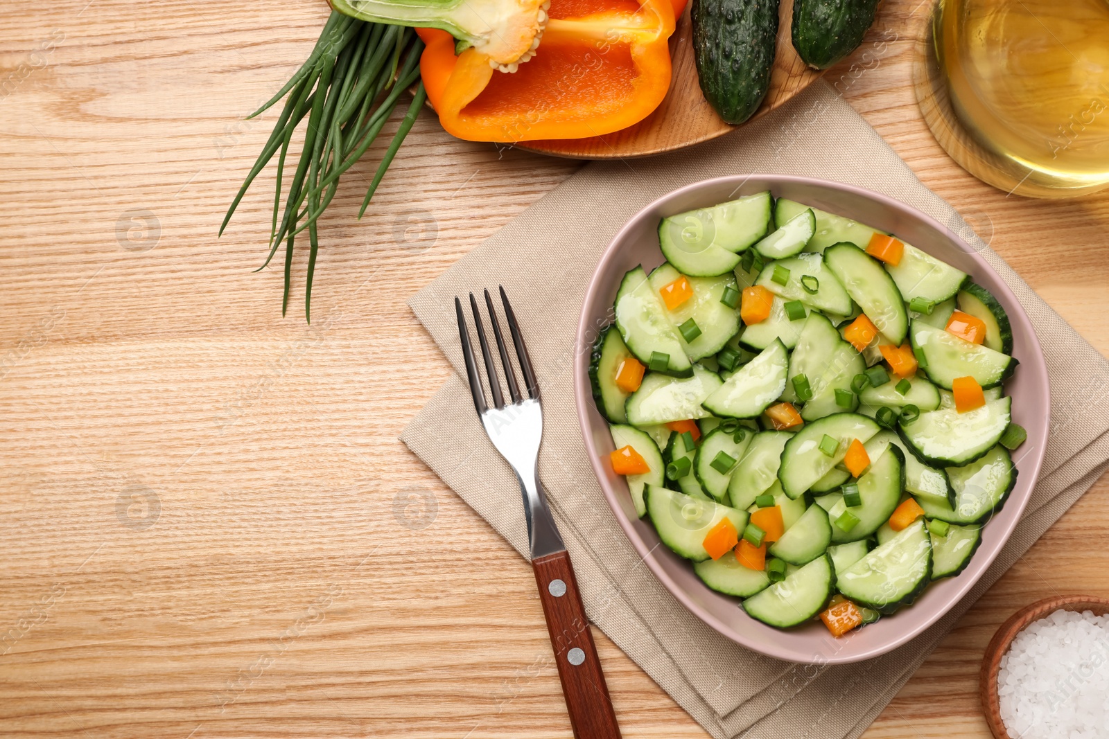 Photo of Tasty fresh salad with cucumber served on wooden table, flat lay. Space for text