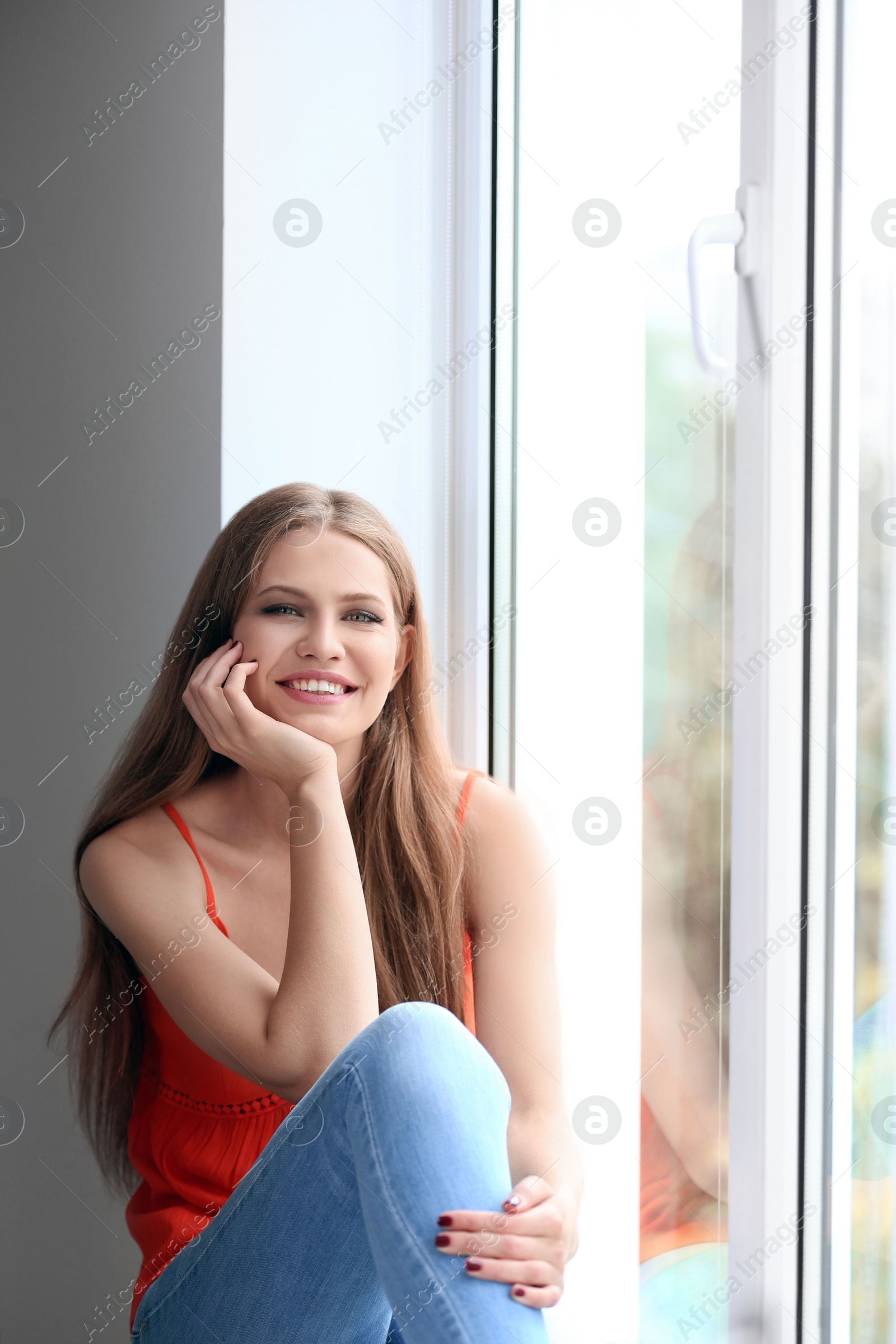 Photo of Young happy woman sitting near window at home