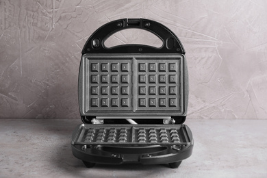 Photo of Modern waffle iron on grey stone table