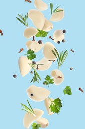 Image of Fresh peeled garlic cloves, peppercorns and different herbs flying on light blue background