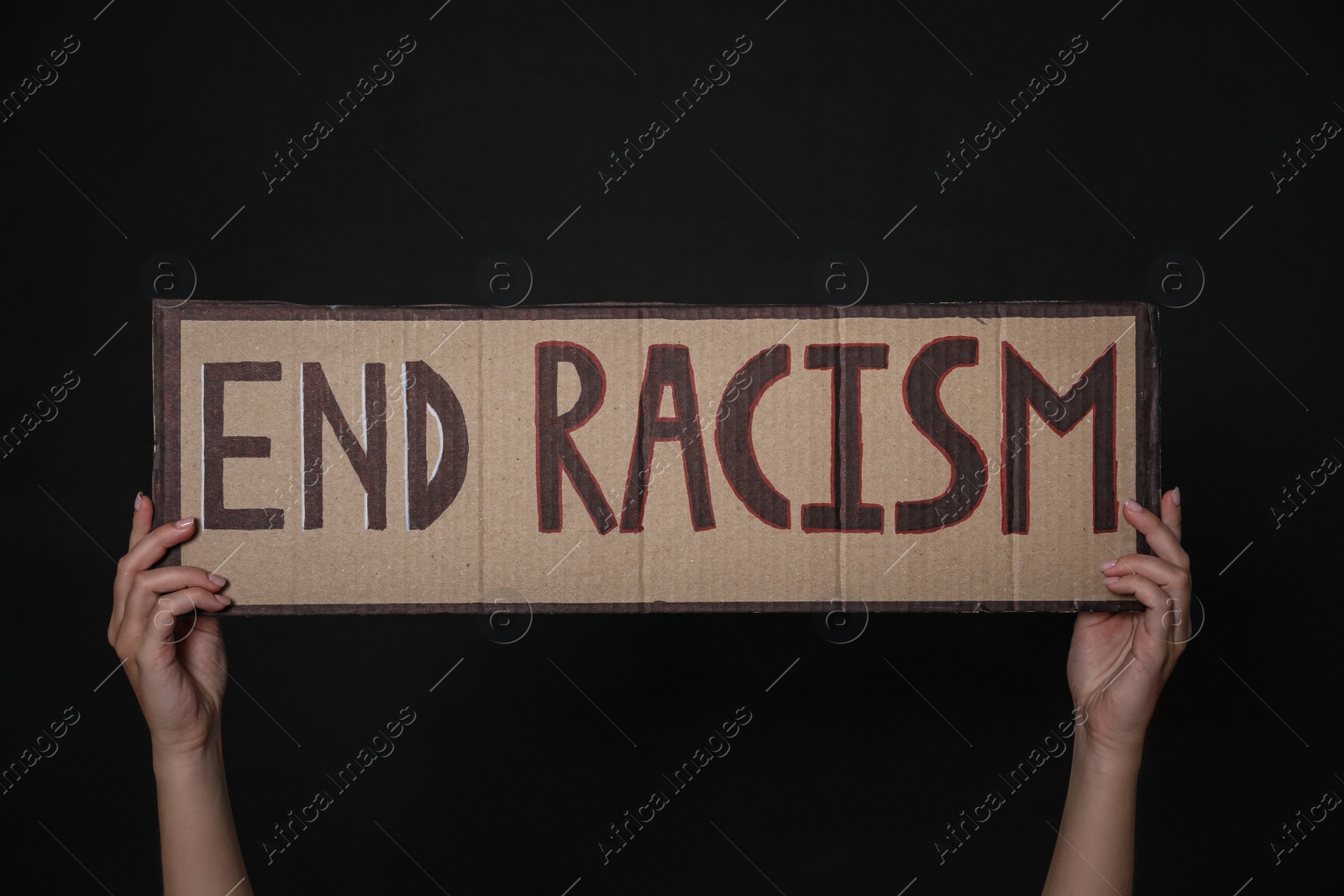Photo of Woman holding sign with phrase End Racism on black background, closeup