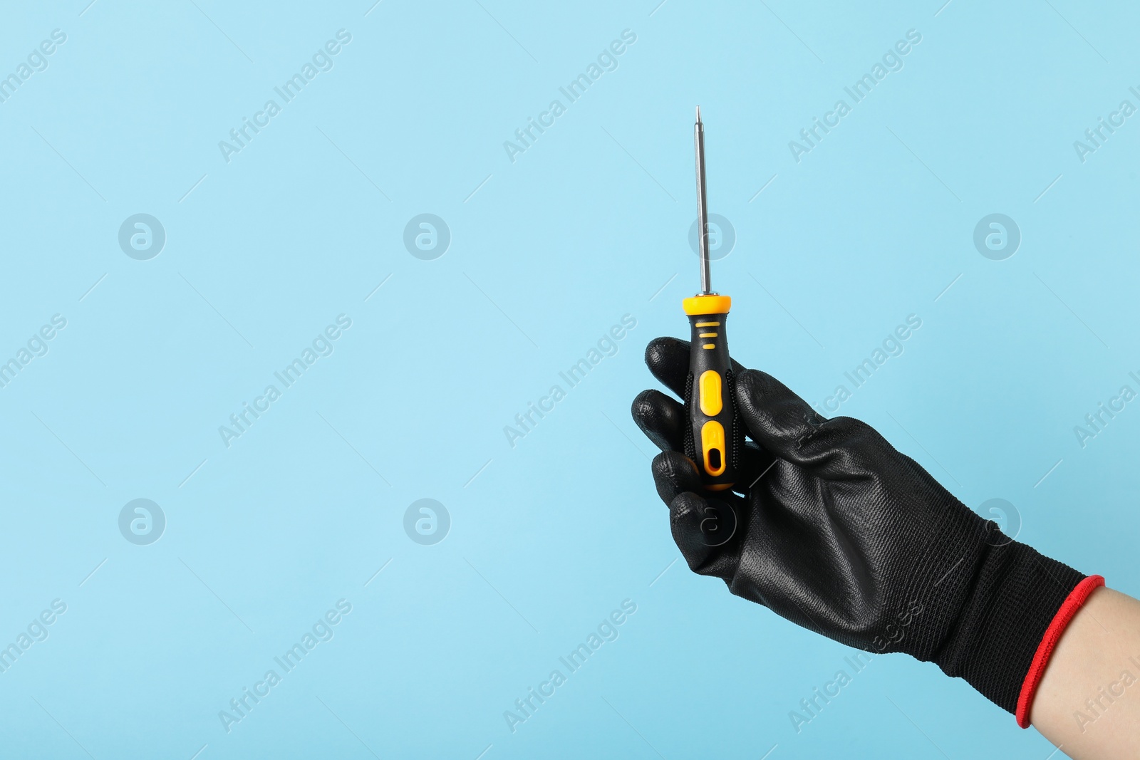 Photo of Woman holding screwdriver on light blue background, closeup. Space for text