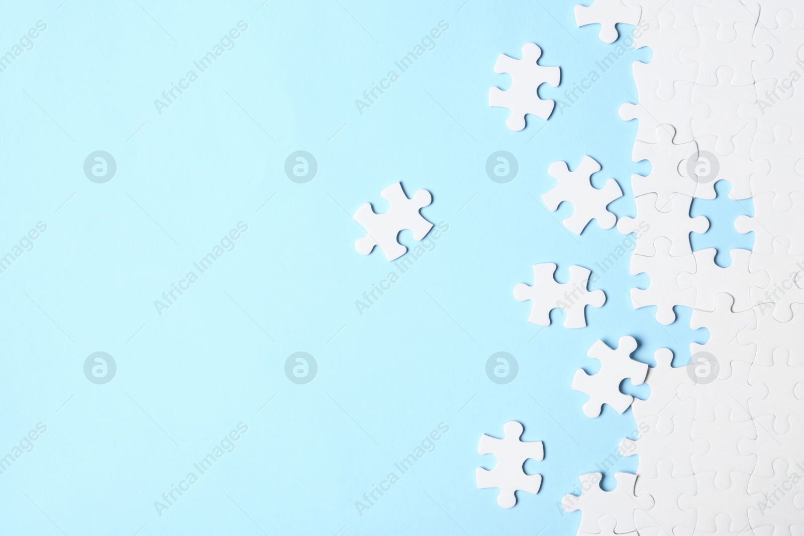 Photo of Blank white puzzle pieces on light blue background, flat lay. Space for text