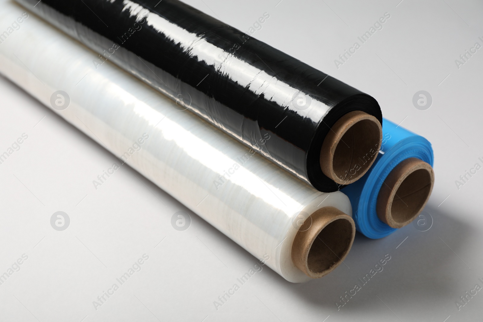 Photo of Rolls of different stretch wrap on light grey background, closeup