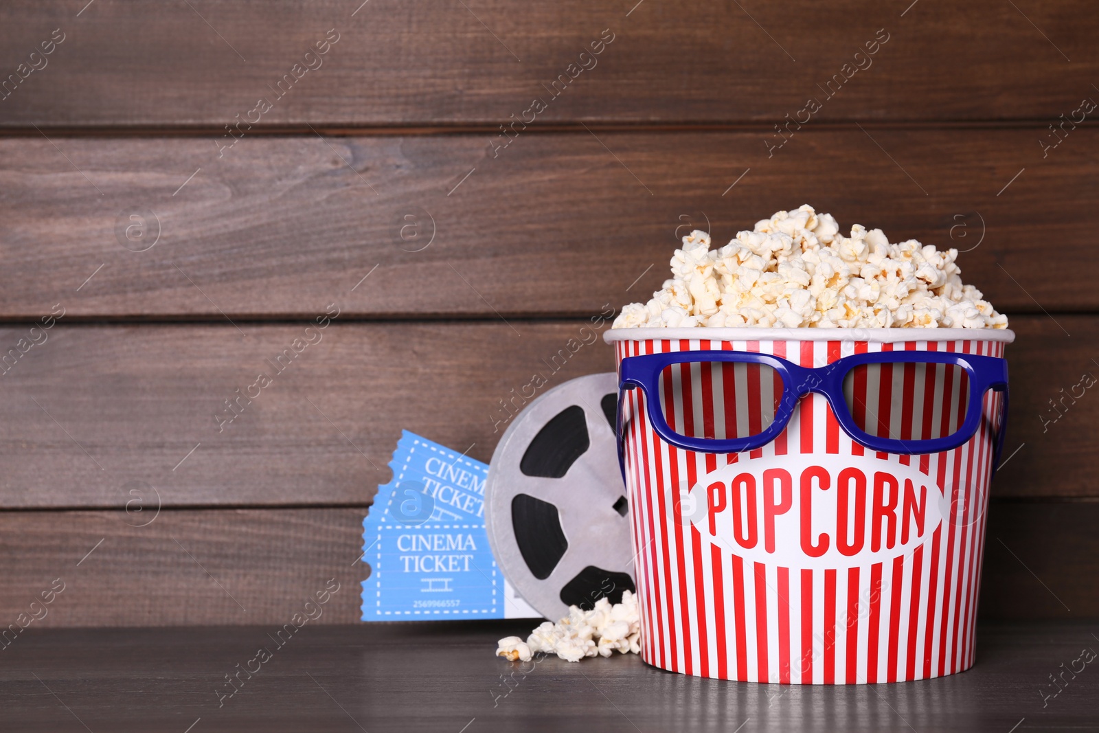 Photo of Delicious popcorn, 3D glasses, movie reel and tickets on wooden table. Space for text