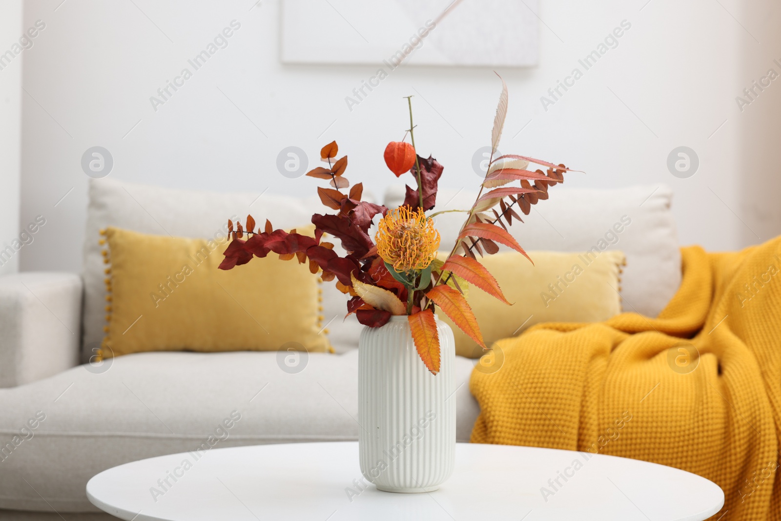 Photo of Vase with bouquet on side table and comfortable sofa in living room
