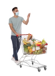 Photo of Man with protective mask and shopping cart full of groceries on white background