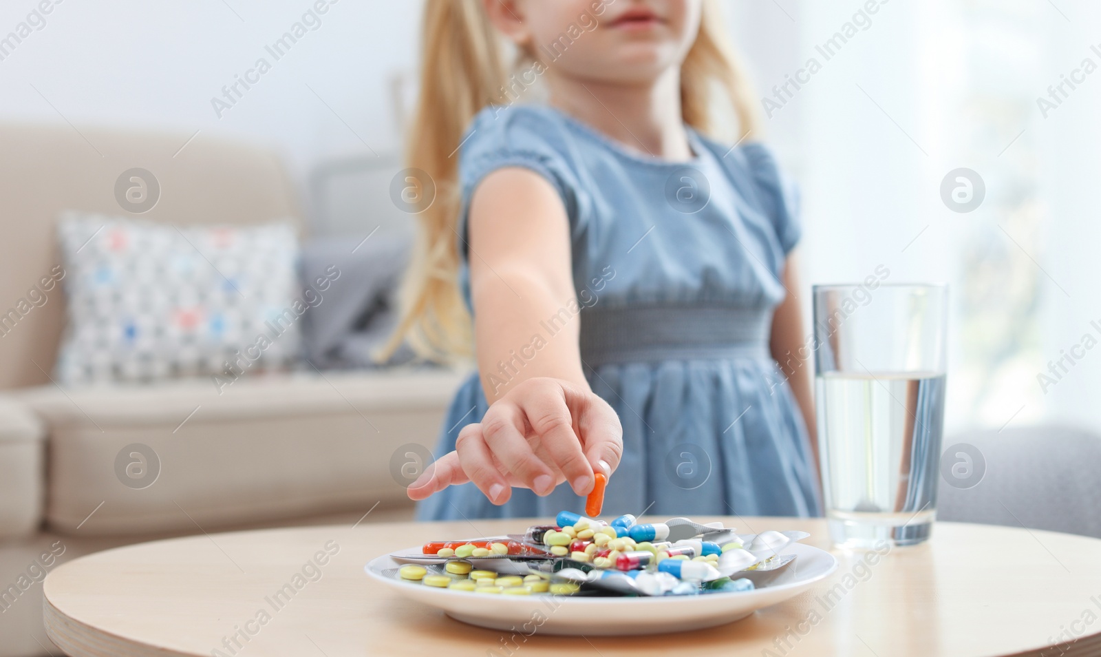 Photo of Little child taking pill from plate at home. Household danger