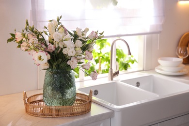 Photo of Bouquet of beautiful flowers on countertop in kitchen, space for text. Interior design