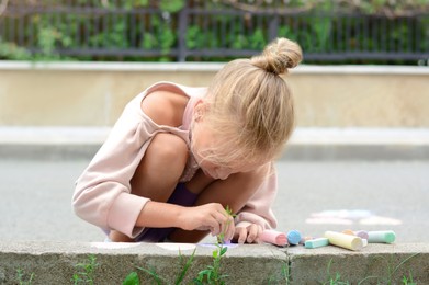 Photo of Little child drawing with chalk on curb outdoors