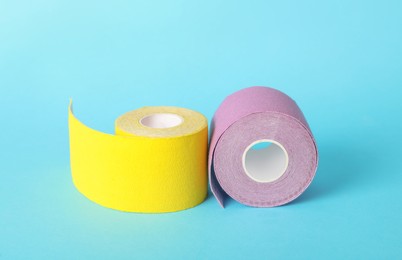 Photo of Bright kinesio tape in rolls on light blue background