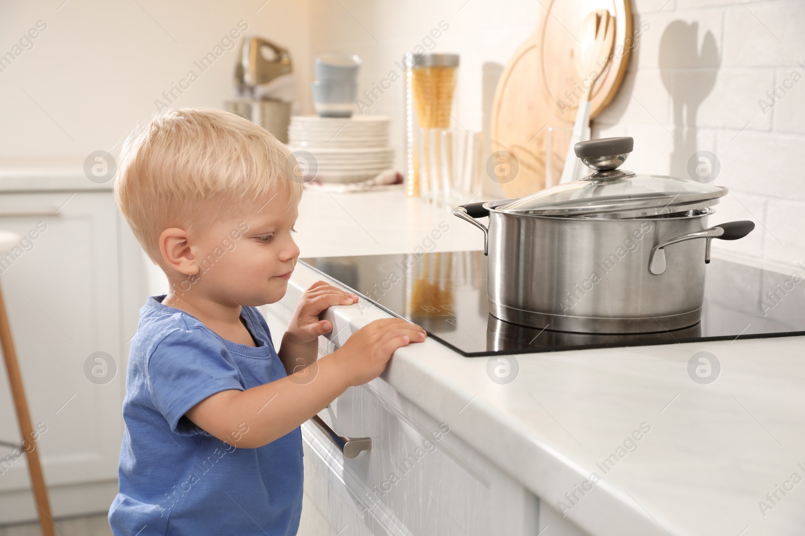 Photo of Curious little boy exploring electric stove in kitchen