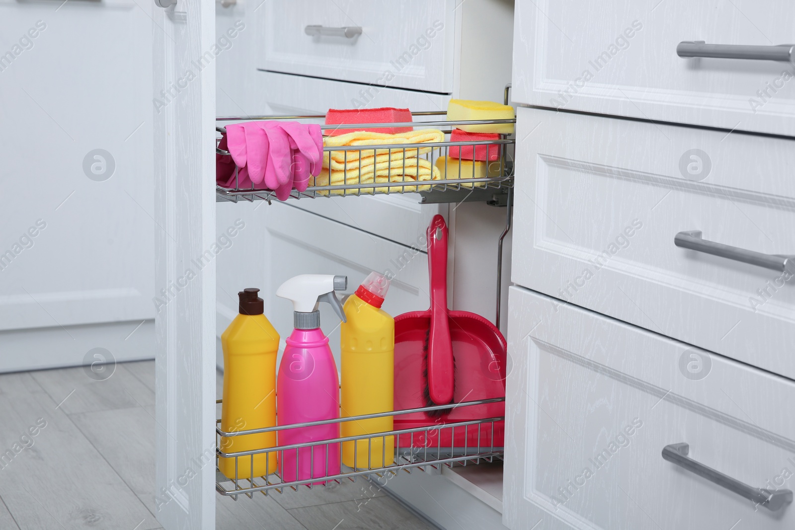 Photo of Open drawer with different cleaning supplies in kitchen