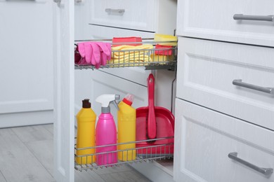 Photo of Open drawer with different cleaning supplies in kitchen