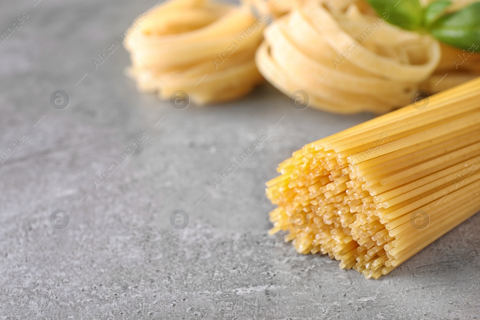 Photo of Uncooked spaghetti on grey table, space for text. Italian pasta
