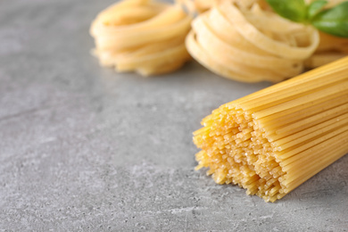 Uncooked spaghetti on grey table, space for text. Italian pasta