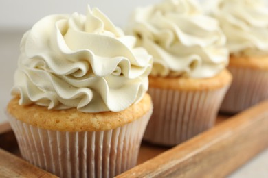 Photo of Tasty cupcakes with vanilla cream on table, closeup