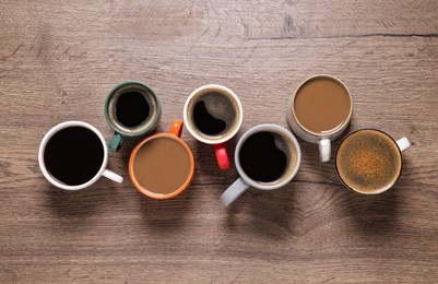 Photo of Cups of hot coffee on wooden table, flat lay