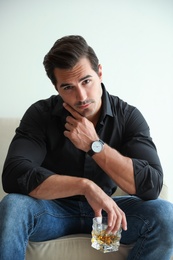 Photo of Young man with glass of whiskey at home