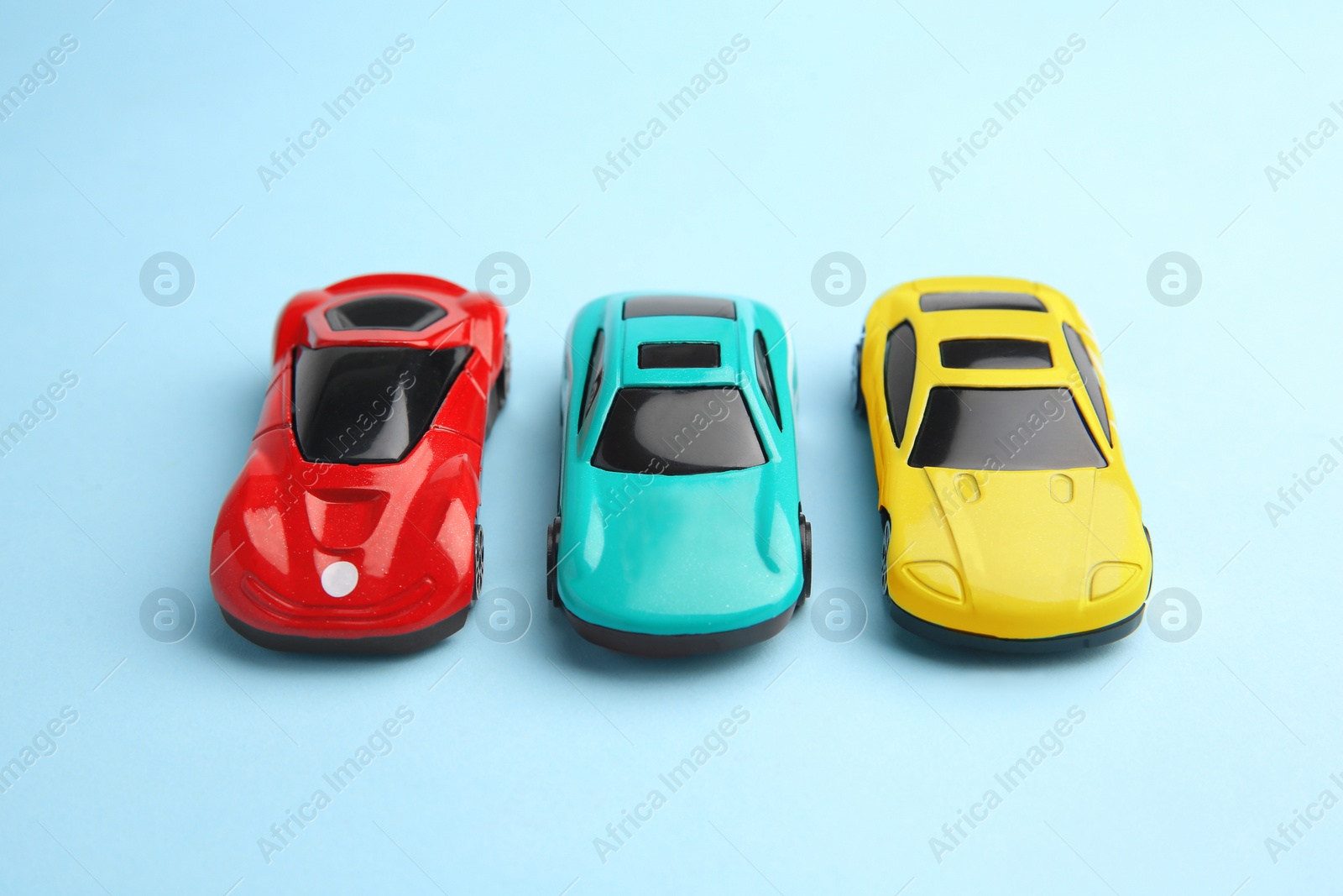 Photo of Different bright cars on light blue background. Children`s toys