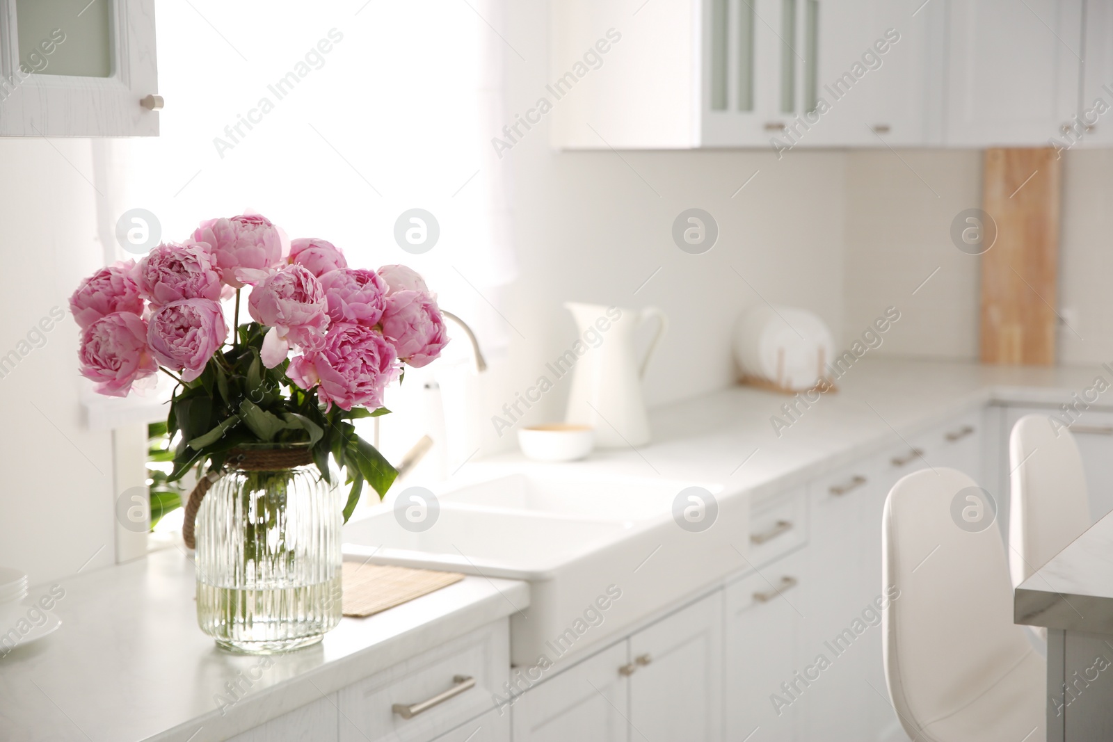 Photo of Vase with bouquet of beautiful pink peonies in kitchen. Space for text