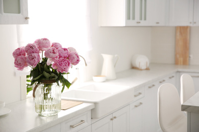 Photo of Vase with bouquet of beautiful pink peonies in kitchen. Space for text