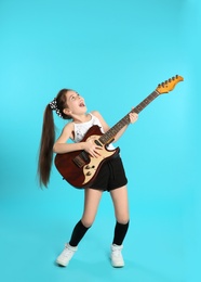 Cute little girl playing guitar on color background