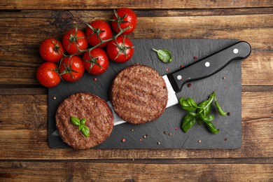 Photo of Tasty grilled hamburger patties served on wooden table, flat lay