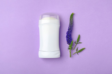 Photo of Deodorant and flower on color background, top view