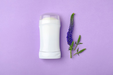 Deodorant and flower on color background, top view