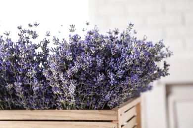 Photo of Fresh lavender flowers in wooden crate on blurred background, closeup view